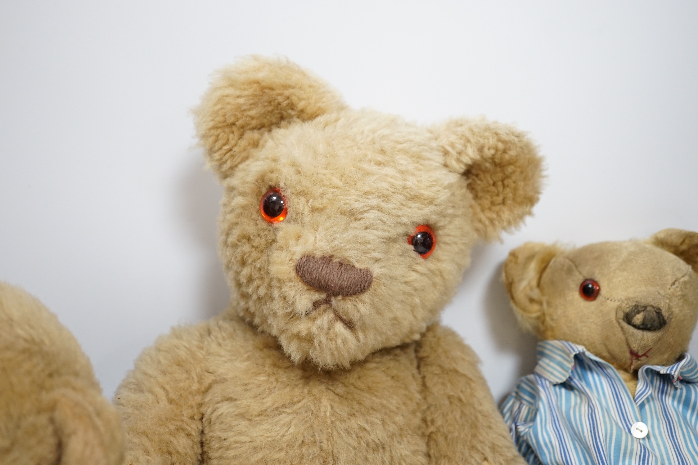 Two Invicta bears, 30cm and 45cm, some wear, and a Merrythought bear, dressed in vintage dressing gown and pyjamas, 32cm high, with hair loss